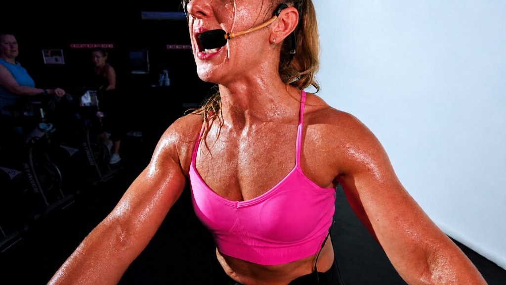 Fitness instructor wearing an EMic headset microphone during an indoor cycling class